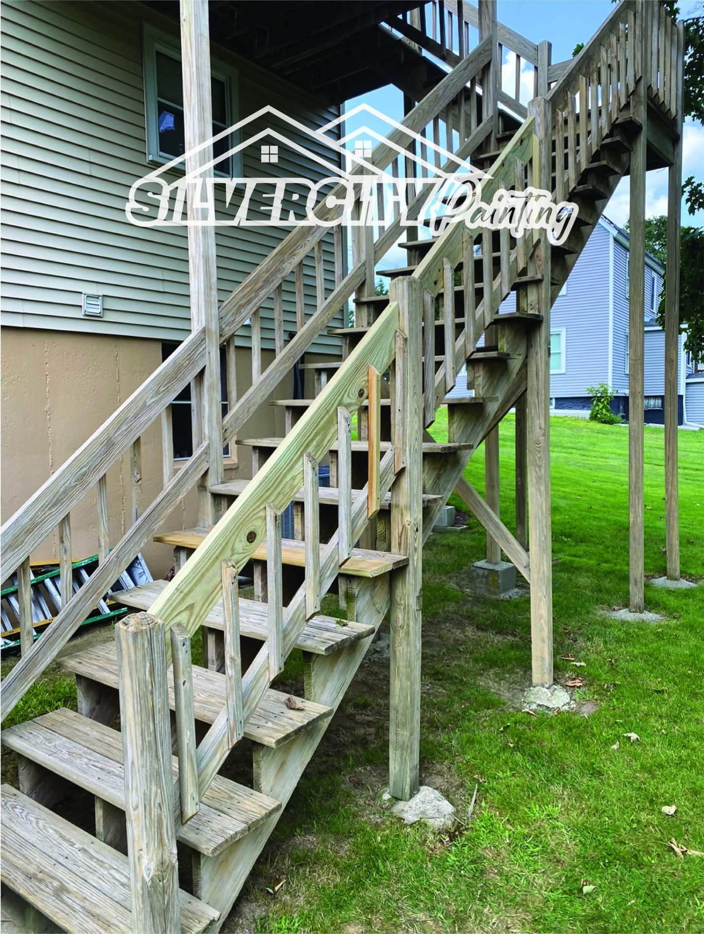 Before staining — grey weathered two-story pressure-treated deck staircase