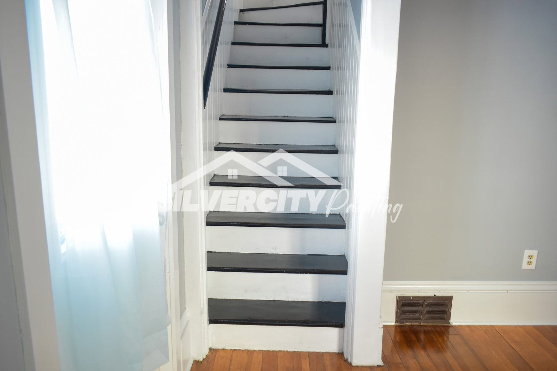 Interior staircase with white painted risers, dark charcoal treads and a repainted stairwell
