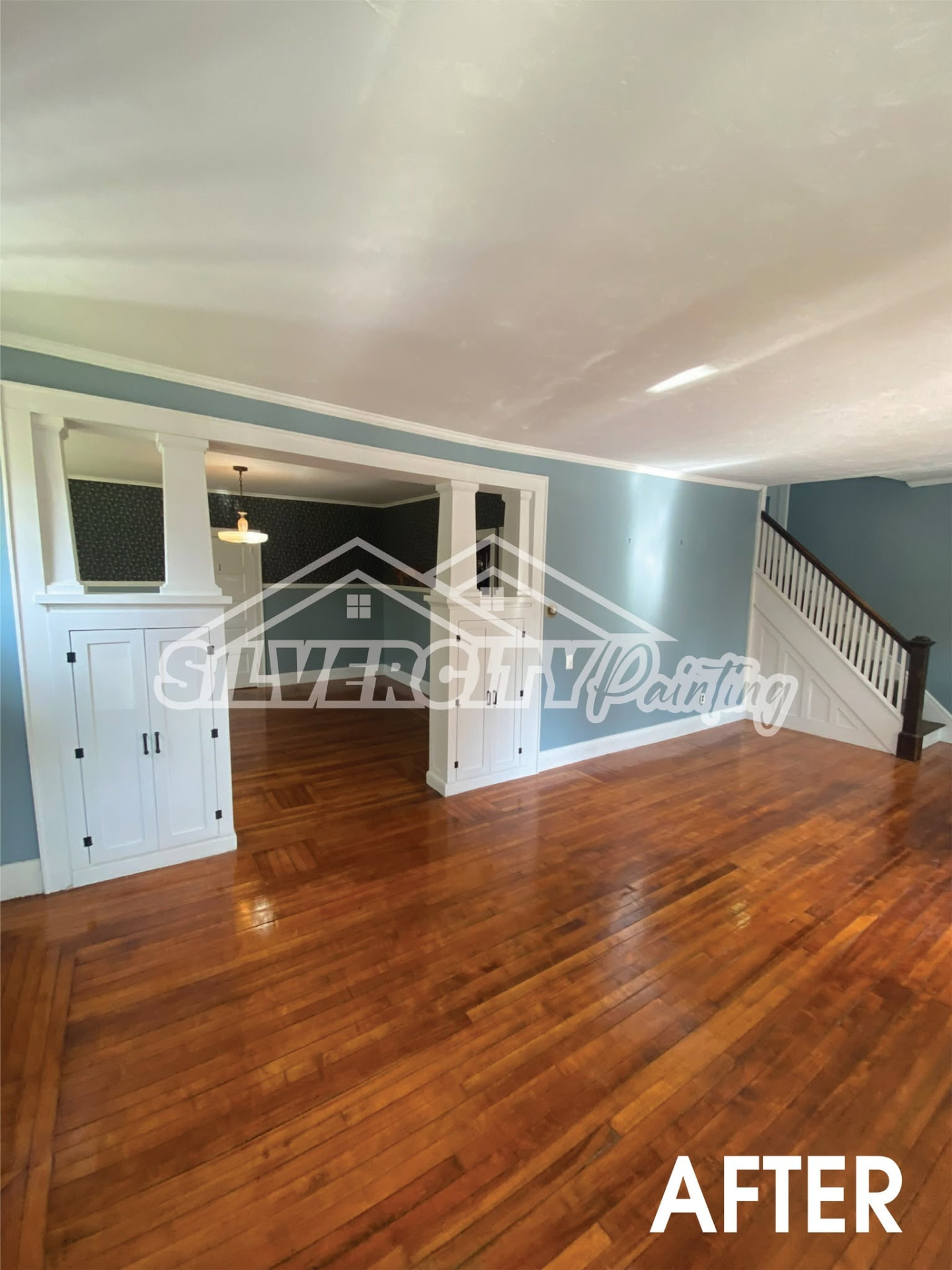 Living room painted slate blue with white trim and built-ins after an interior repaint