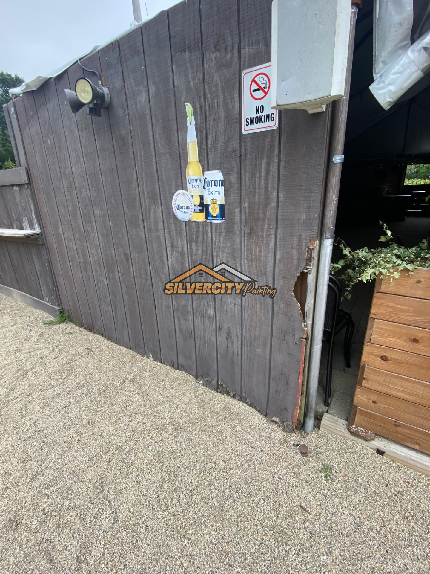 Before painting — faded grey wood dumpster enclosure fence at a commercial property in Taunton, MA